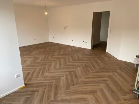 Im Fischgrätmuster verlegter Designboden in einem leeren Wohnraum