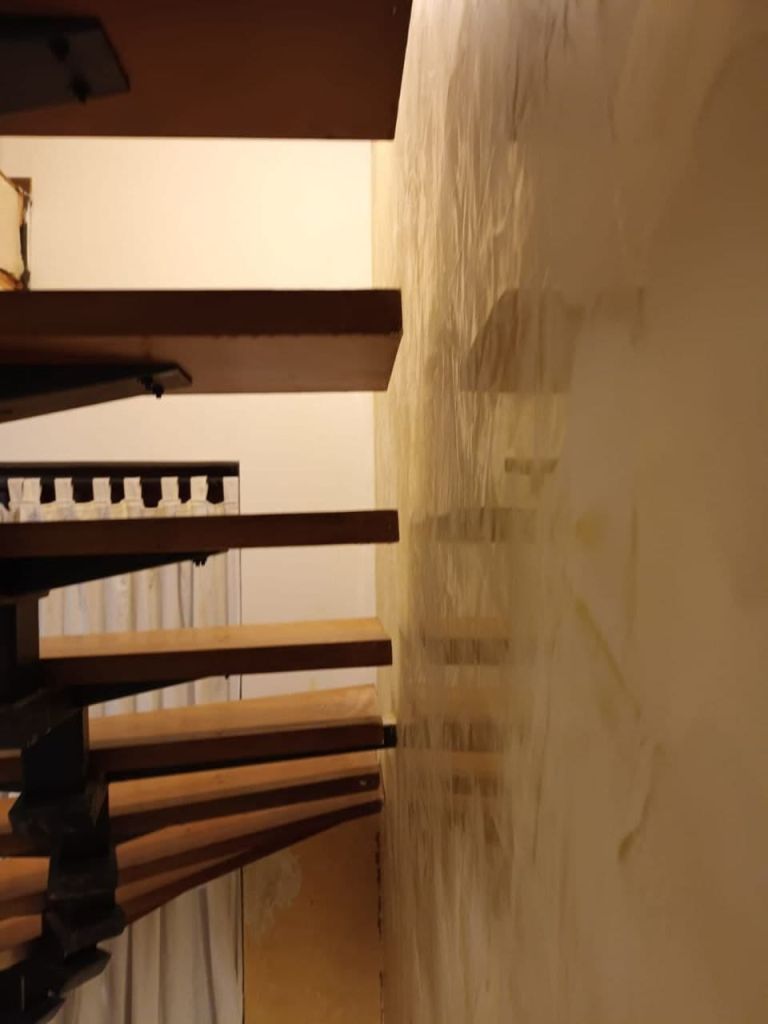 Treppenhaus während der Wandarbeiten mit alter Holztreppe und frisch aufgezogener Wandfläche