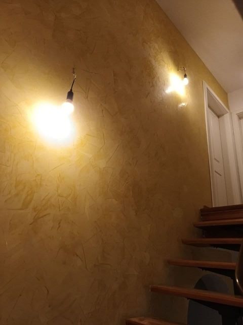 Von Hand aufgezogene Wandfläche in warmem Goldton neben einer originalen Holztreppe